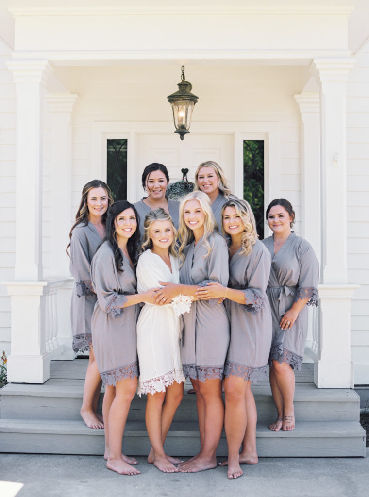 Bride posing with her seven bridesmaids in their matching robes.